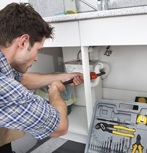 Plumber Fixing Sink In Kitchen